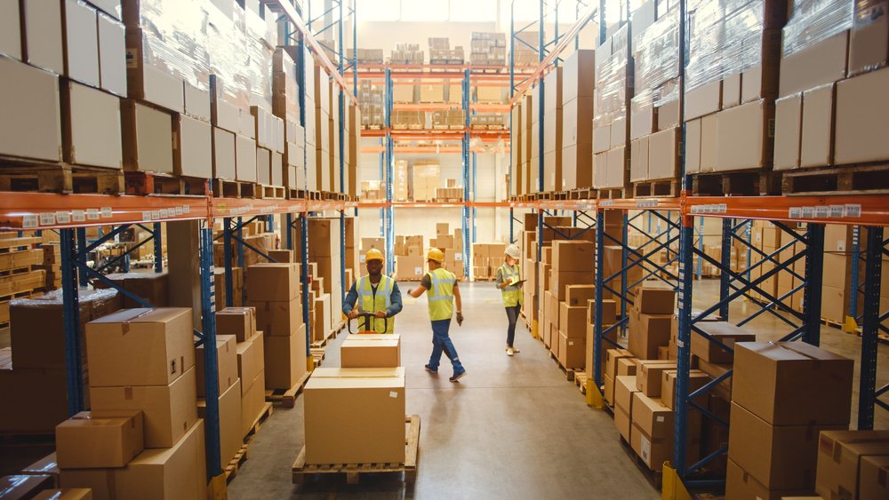 Warehouse staff walking an aisle of stacked pallet racking